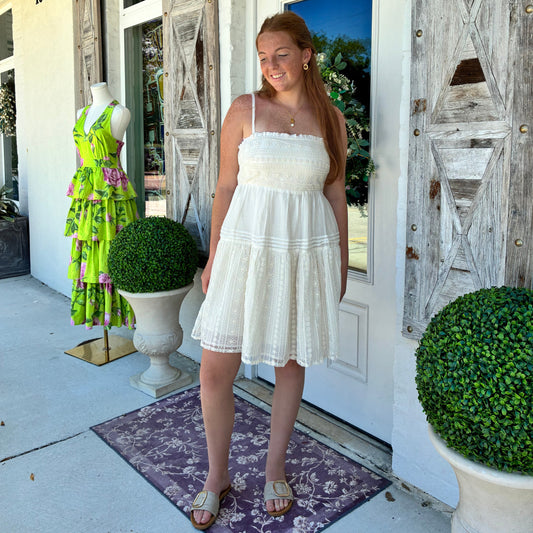 A woman wearing an ecru sleeveless tiered mini dress 