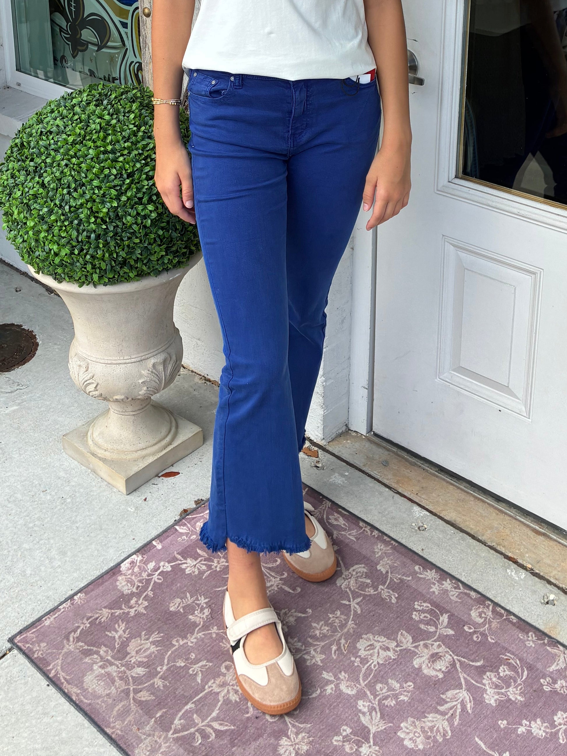 A young women wearing a Royal or Colbalt colored flare ankle jeans with a raw edge
