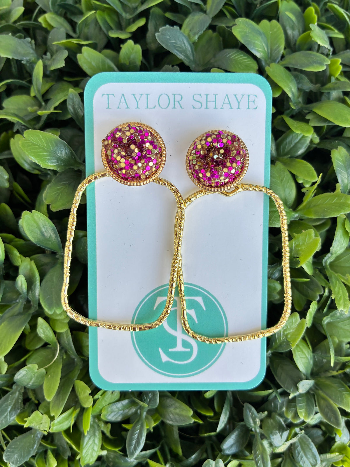 purple and gold glitter rectangle earrings on a leaf backdrop