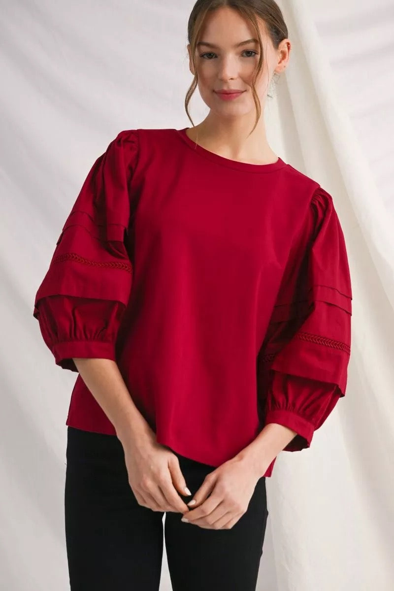 Woman wearing a red blouse with puff sleeves against a white background