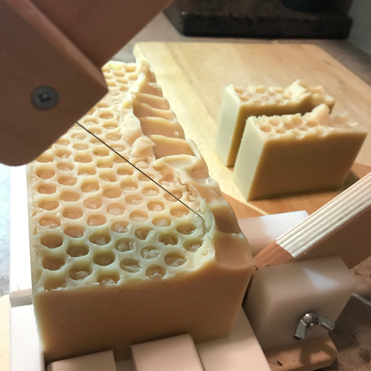 Oatmeal honey soap loaf being cut into bars