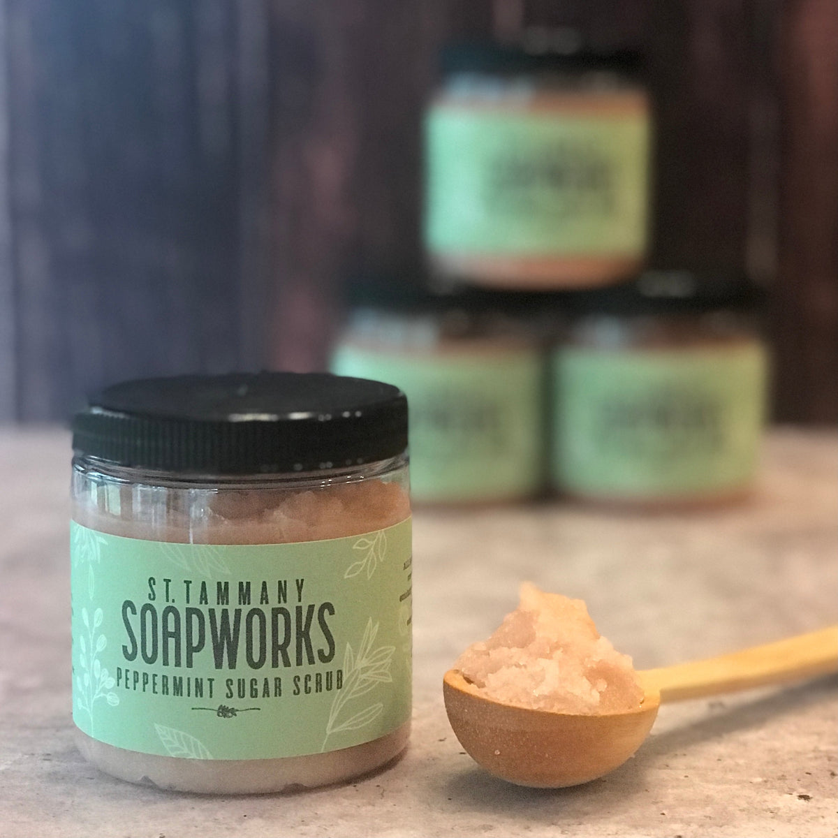 Stacked jars of Peppermint Sugar Scrub with a scoop of scrub