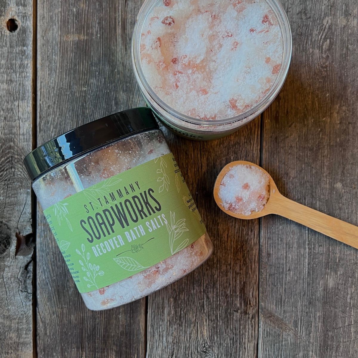 Tipped jar of RECOVER Bath Salts with a scoop of salts