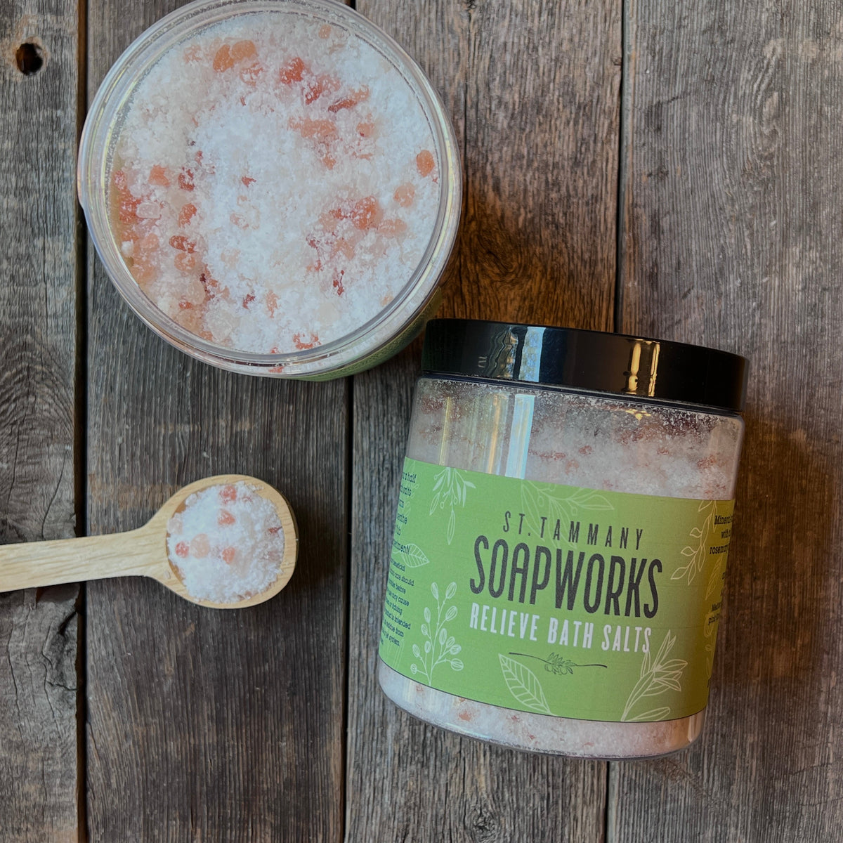 Open jar of RELIEVE Bath Salts with a wooden scoop of salts