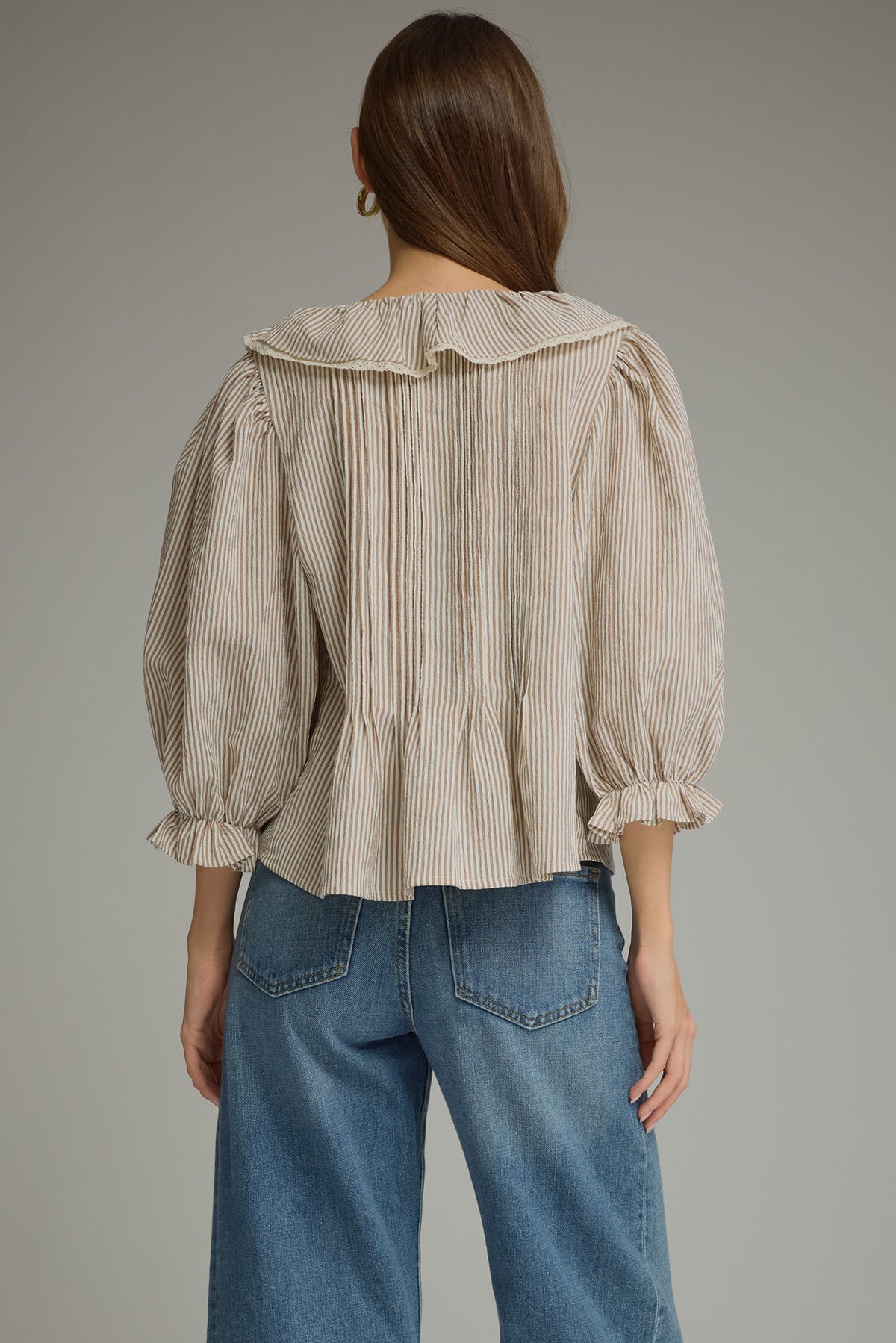 Back view of brown pinstripe blouse with ruffle collar and pleated back