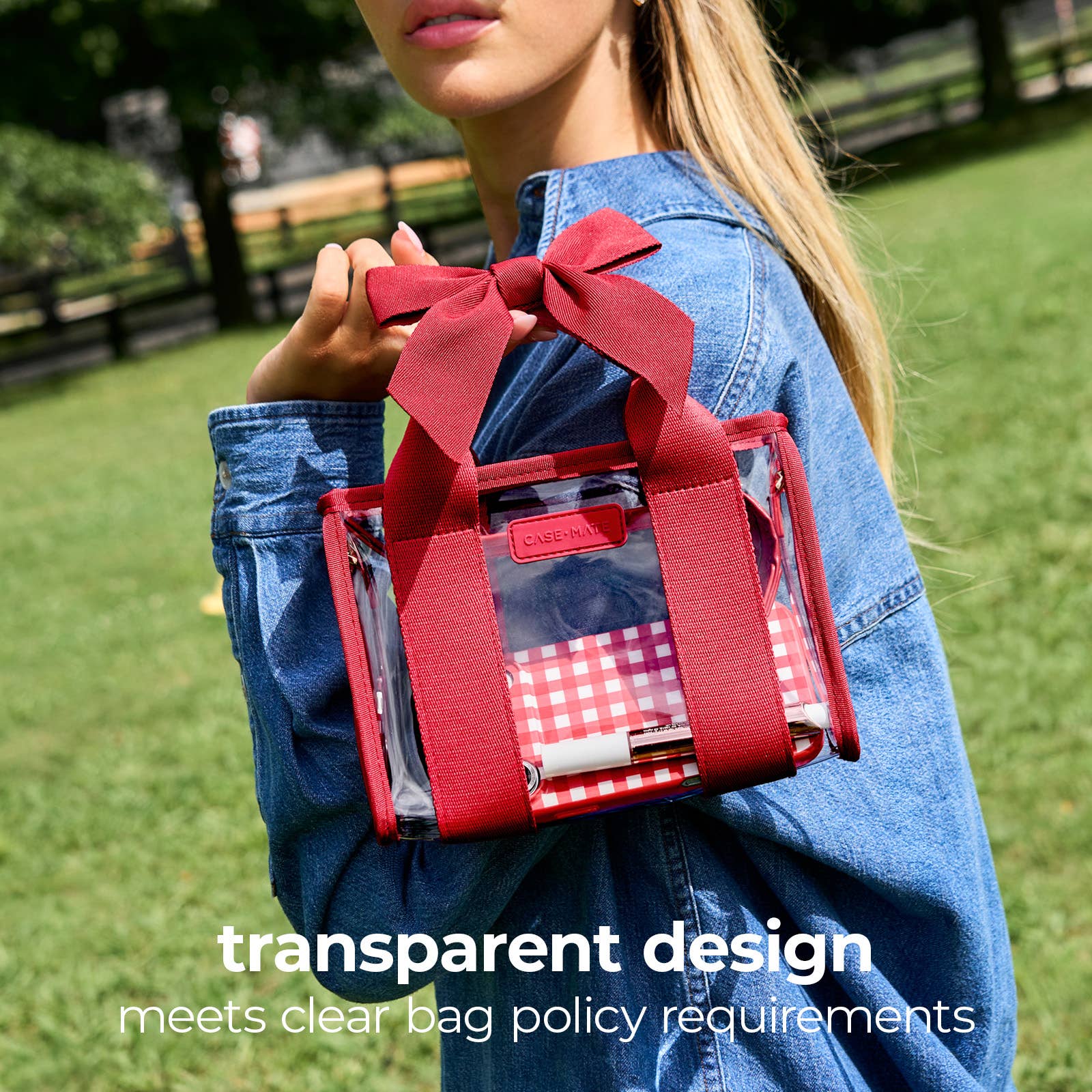 A woman outdoors in a park holding a small transparent plastic bag with red handles and a red bow. The bag has a red-and-white gingham patterned insert and text at the bottom reads 'transparent design meets clear bag policy requirements'.
