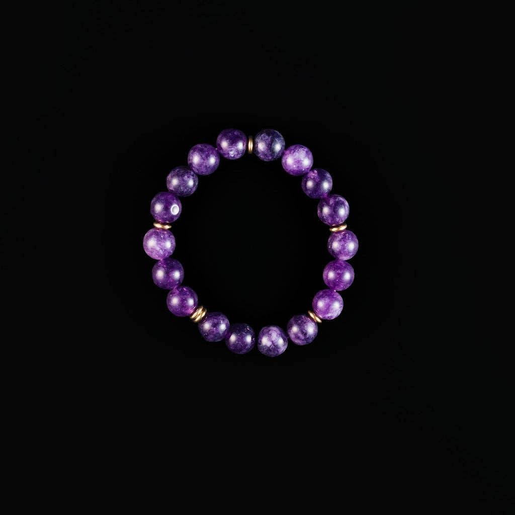 A beaded stretch bracelet made of polished purple amethyst beads separated by small gold spacer rings, displayed against a solid black background.