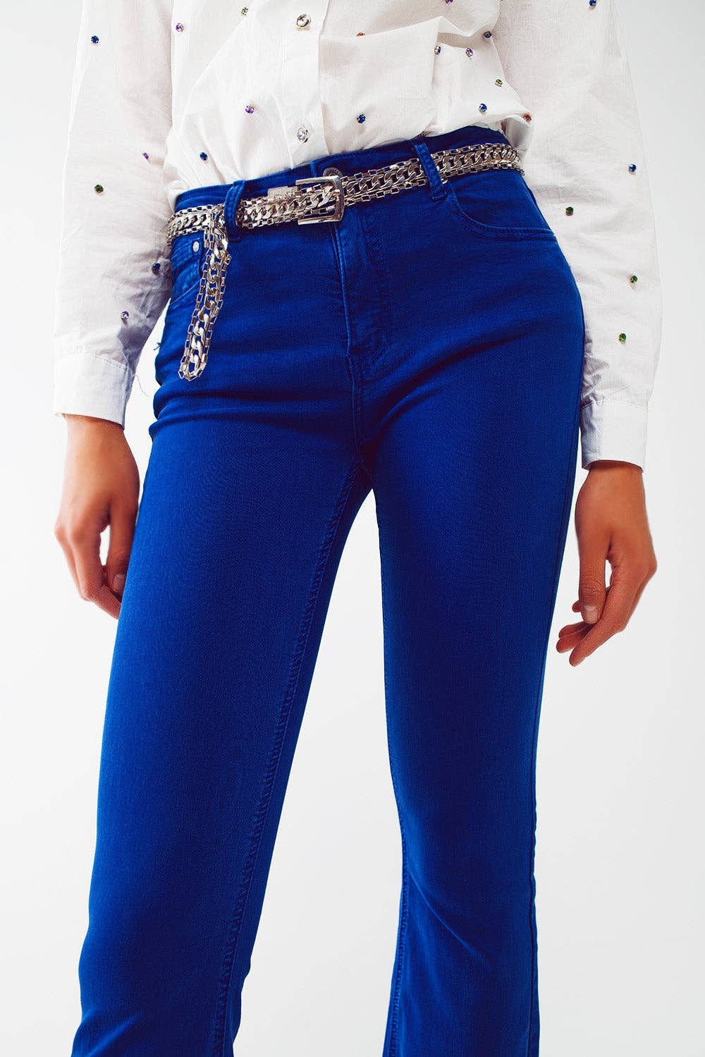 Blue jeans with a silver belt on a white background