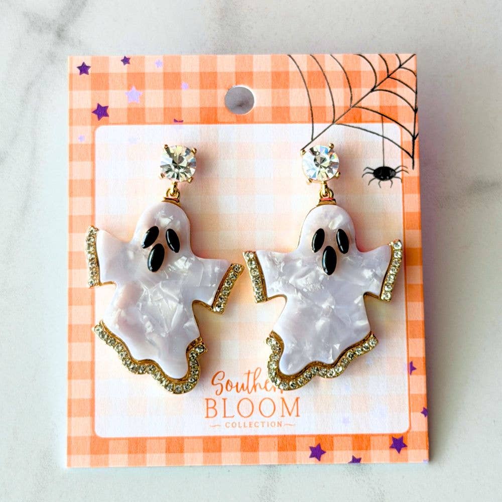 A pair of ghost-shaped dangle earrings displayed on a branded retail card. The earrings have a glossy white ghost with a gold glittery trim, topped with clear rhinestone studs.