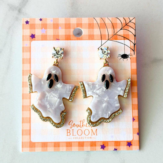 A pair of ghost-shaped dangle earrings displayed on a branded retail card. The earrings have a glossy white ghost with a gold glittery trim, topped with clear rhinestone studs.