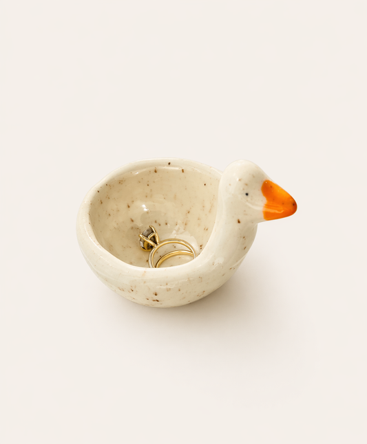 Karlee the Goose ceramic ring dish in speckled cream with an orange beak, holding a gold ring
