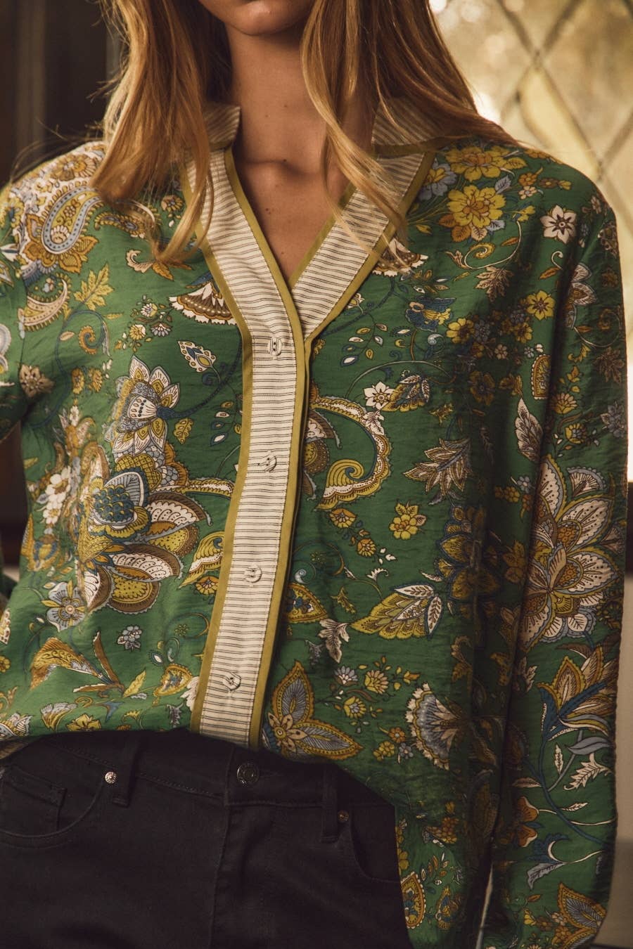 Close-up of green paisley print in gold, cream and blue with striped contrast band placket
