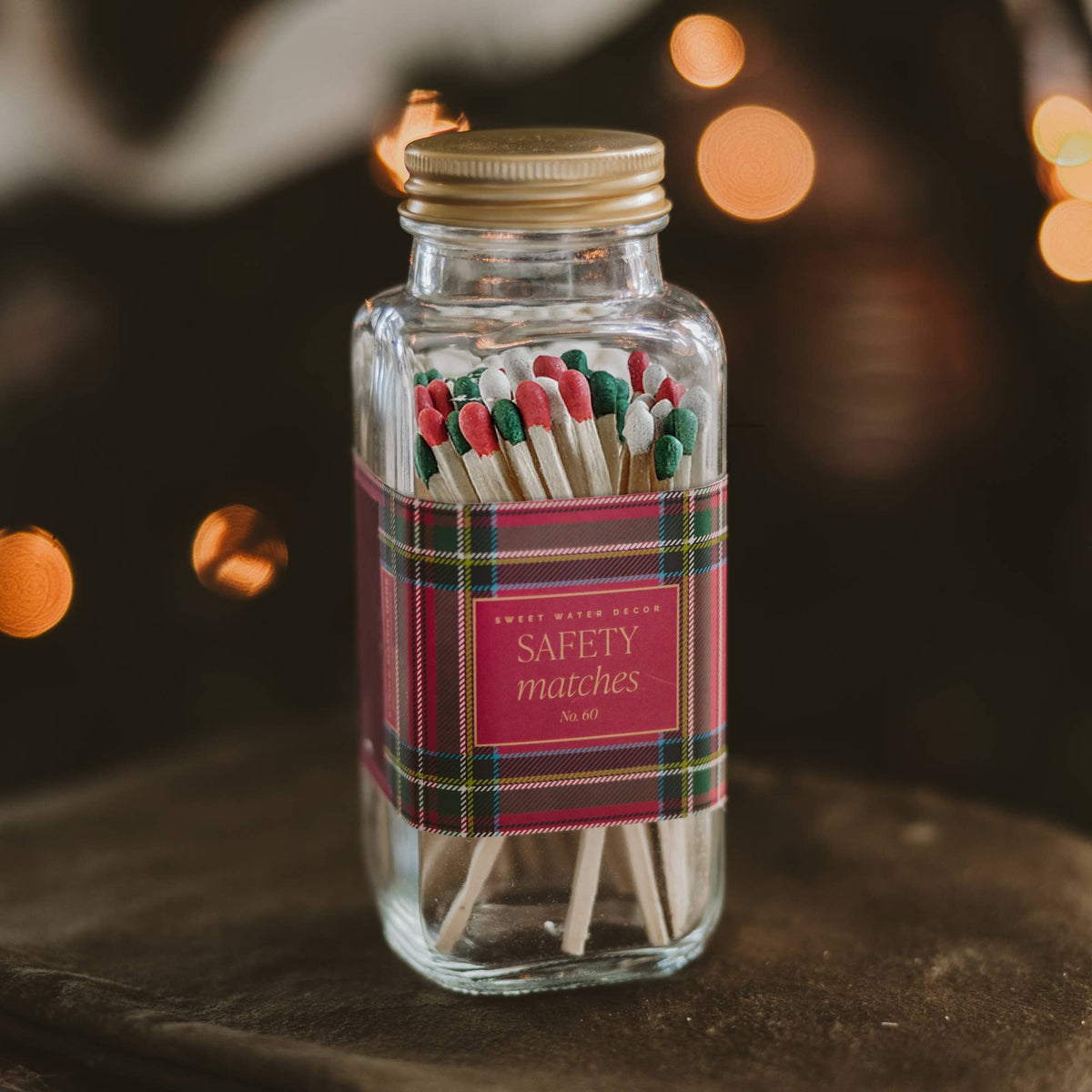 Holiday plaid safety matches with red and green tips by twinkle lights