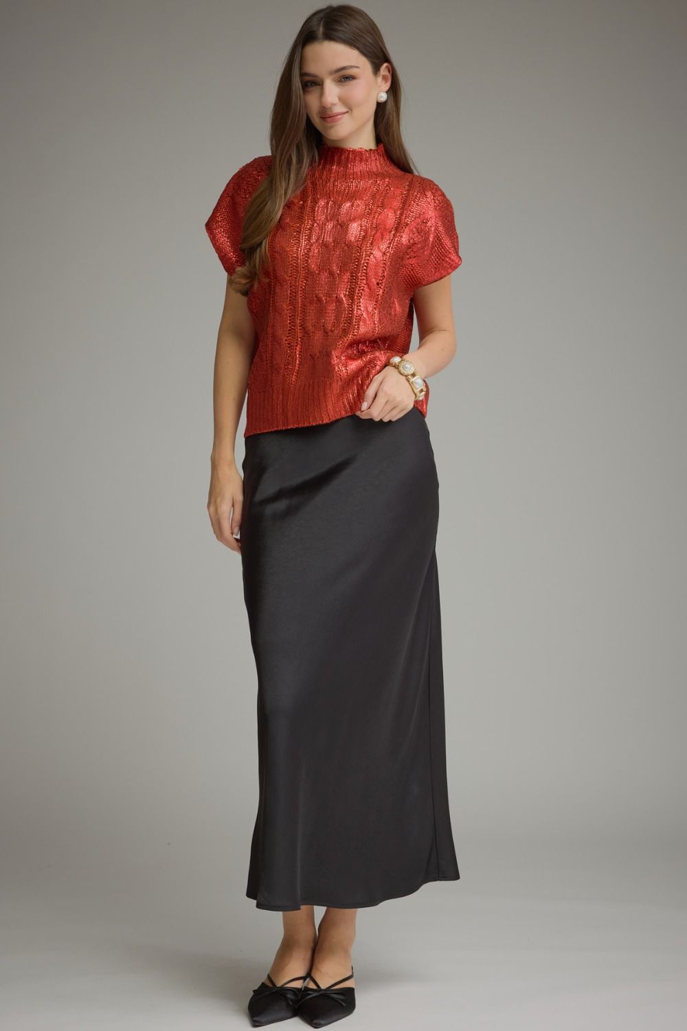 Full-length view of metallic red cable knit sweater top styled with a black skirt