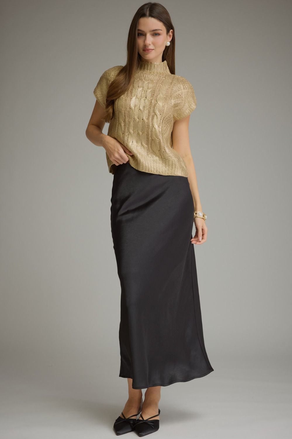 Full-length view of metallic gold cable knit sweater top styled with a black skirt