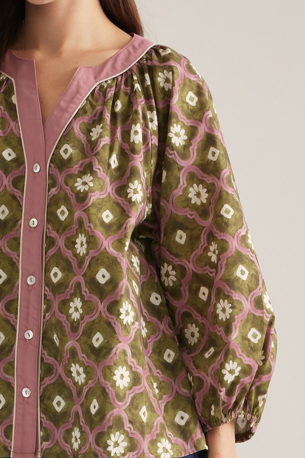 Close-up of olive geo floral print with pink V-neck contrast trim