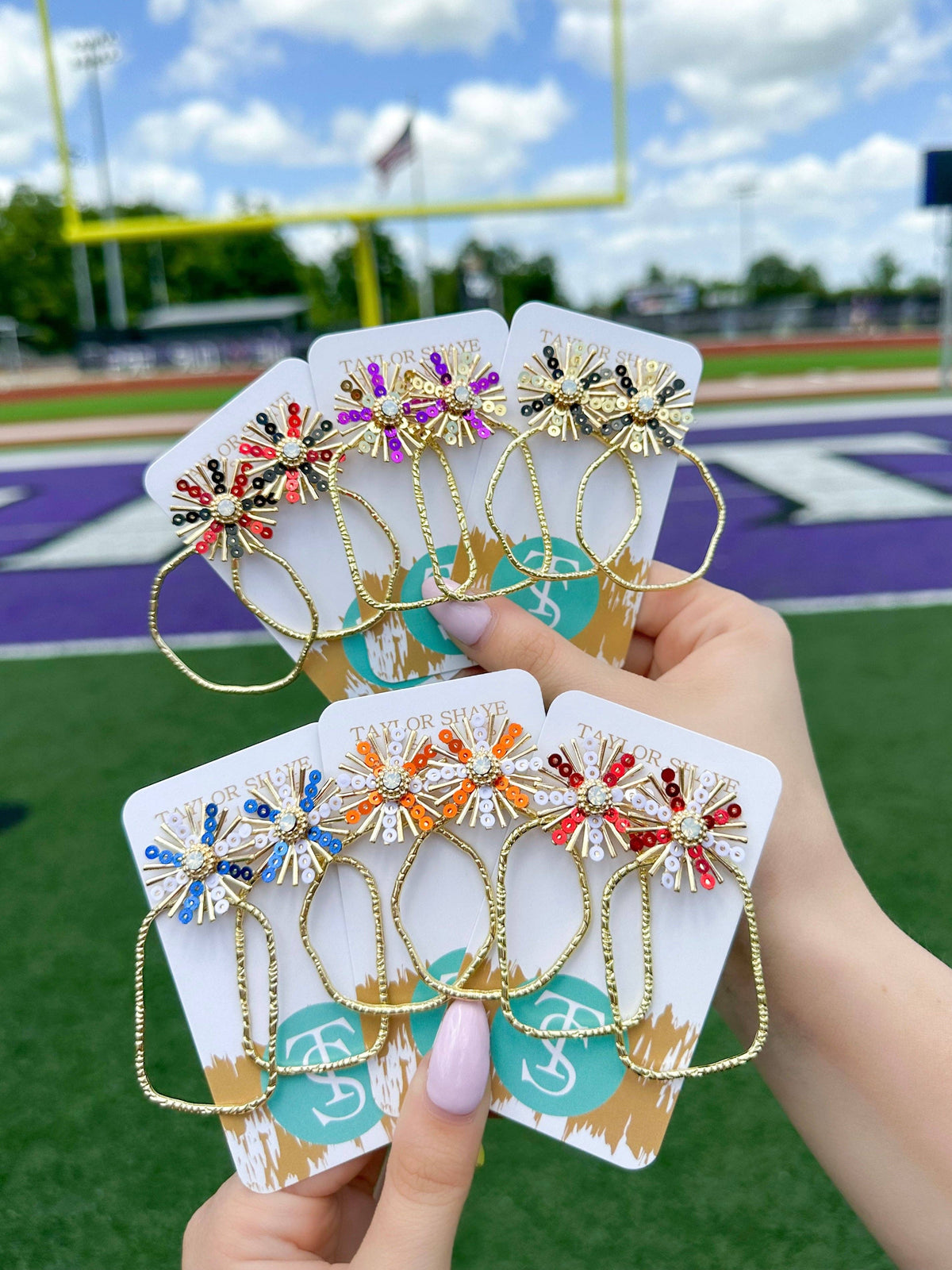 Colorful earrings on display with a sports field background