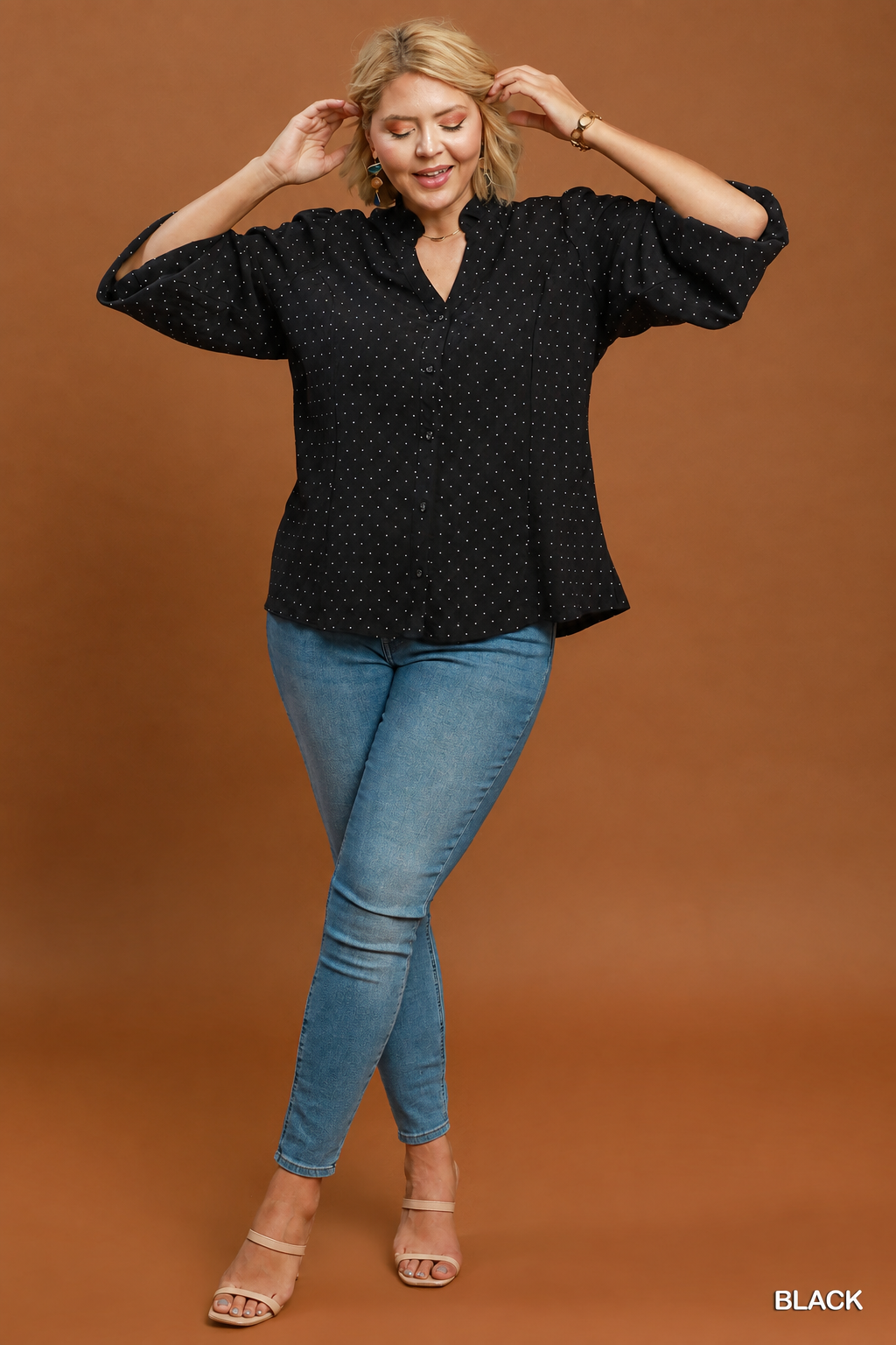 Full-length view of model wearing a black Swiss dot button-front top with jeans