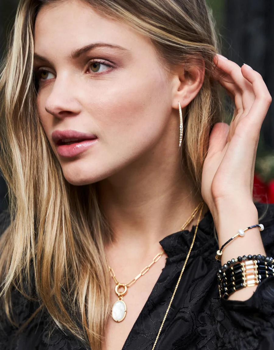 A close-up lifestyle shot of a woman wearing the gold hoop earring.