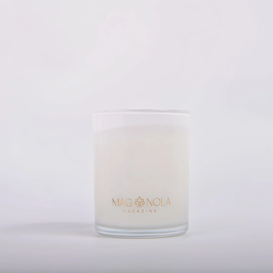 A frosted 8.5 oz glass candle jar with a white wax insert and gold foil branding reading 'MAG NOLA MAGAZINE' on a clean white background.