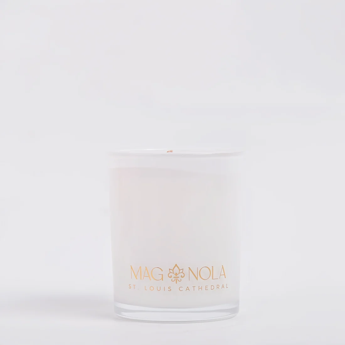 A frosted 8.5 oz glass jar candle with a white wax fill and gold foil branding that reads 'MAG NOLA' and 'ST. LOUIS CATHEDRAL' on a clean white background.
