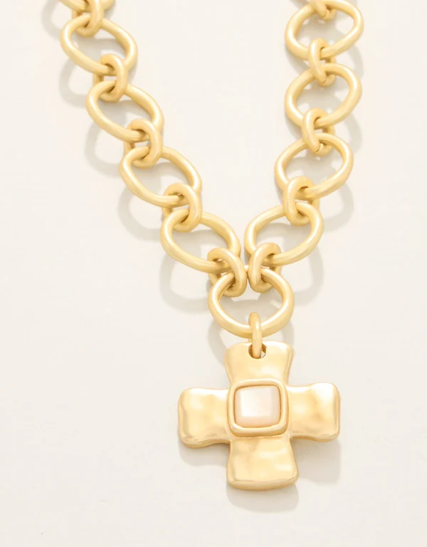 A gold-tone chain necklace with a thick, textured cross pendant featuring a central square inlay, photographed on a clean white background.