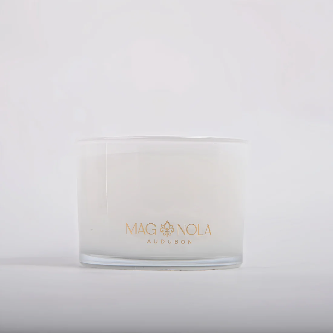 A frosted 14 oz glass jar candle with a gold foil logo reading 'MAG NOLA AUDUBON' on the front, set against a clean white background.