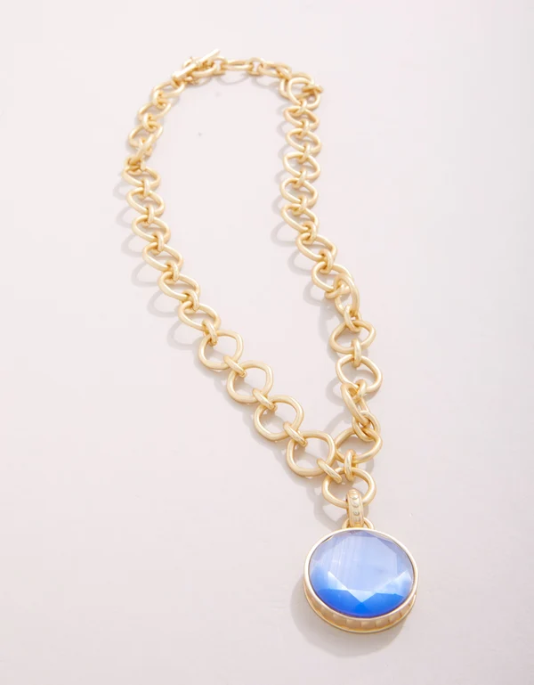 Gold chain necklace with a blue pendant on a light gray background