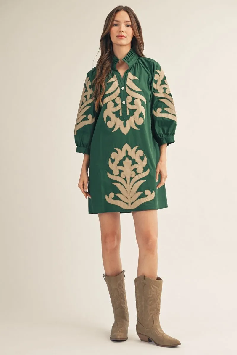 Woman wearing a green dress with beige patterns and brown boots on a white background
