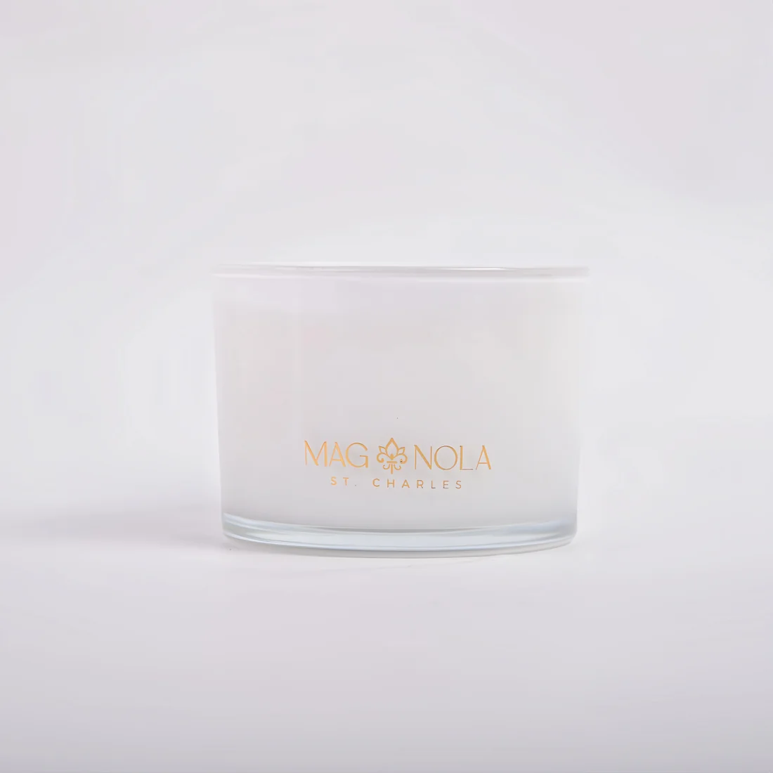 A frosted 14 oz glass jar candle with a clear lid, featuring the brand name 'MAG NOLA ST CHARLES' printed in gold on the front, set against a clean white background.