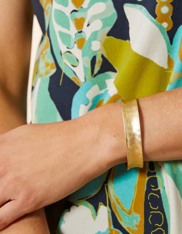 Gold bracelet on a wrist with a colorful patterned garment