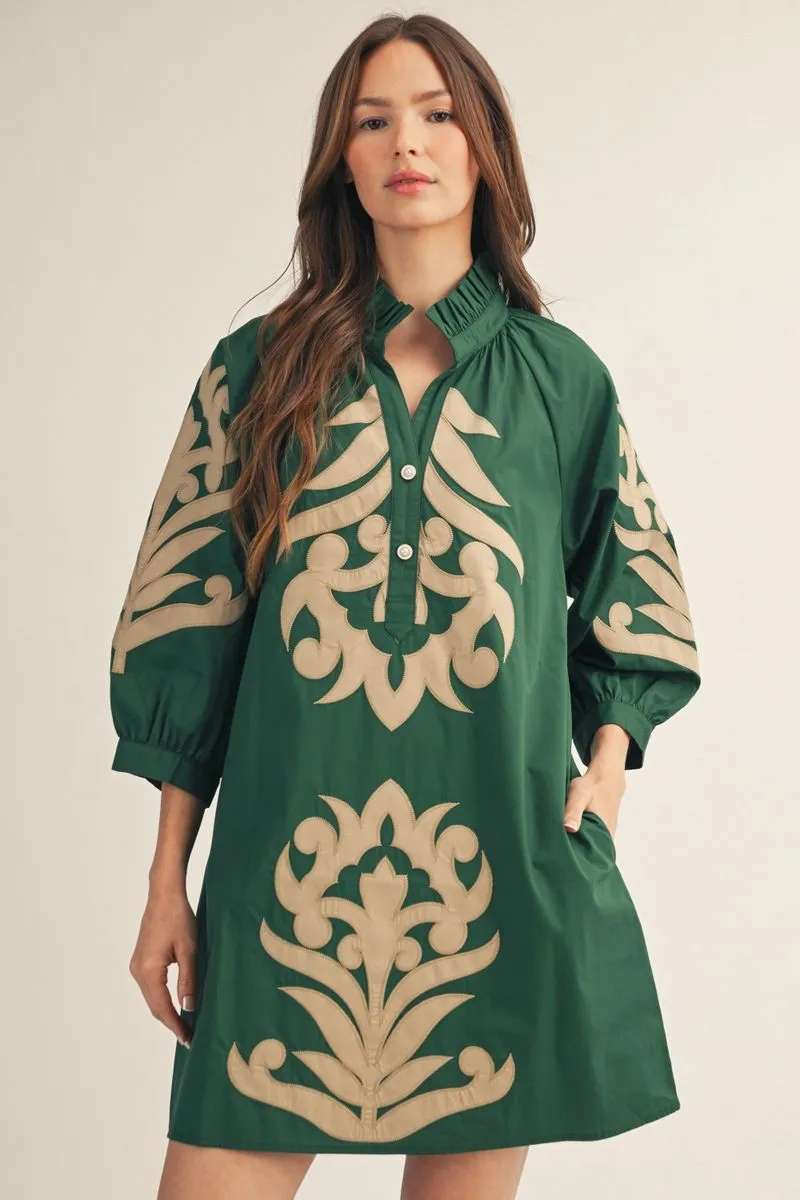Woman wearing a green dress with beige floral patterns on a beige background