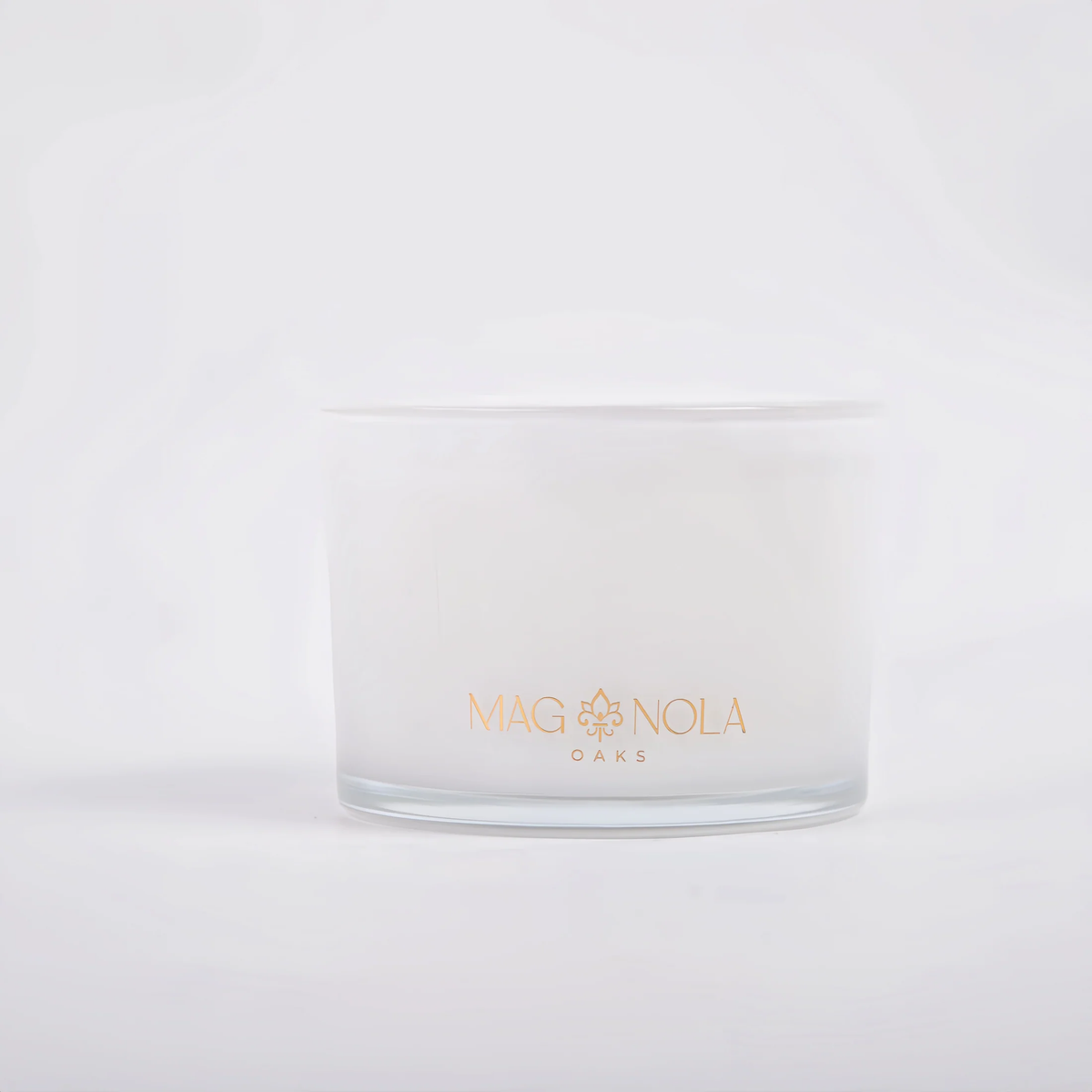 A frosted 14 oz glass jar candle with a gold foil logo reading 'MAG NOLA OAKS' on the front, set against a clean white background.