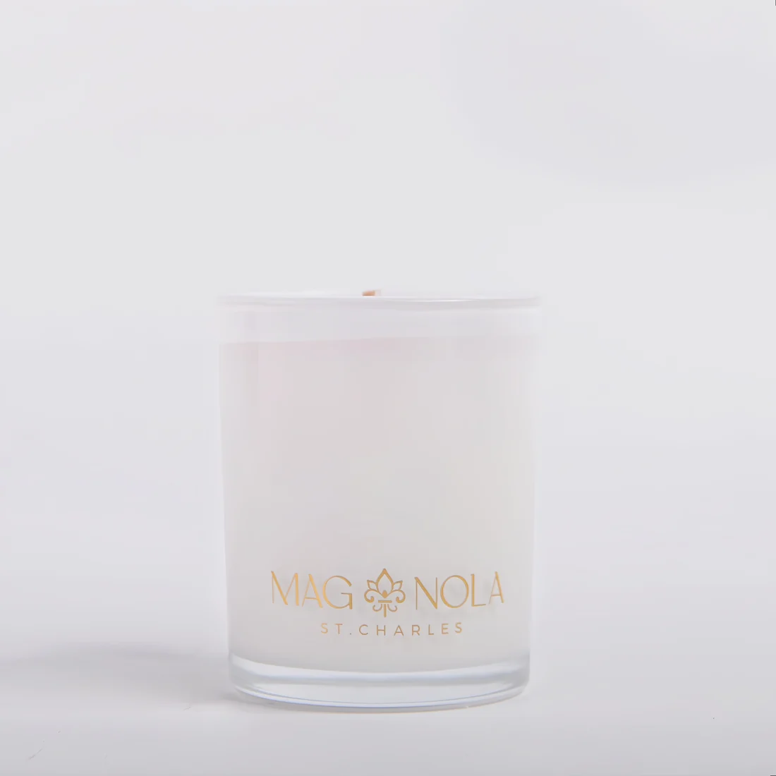 A frosted 8.5 oz glass jar candle with a clear lid, featuring the brand name 'MAG NOLA ST CHARLES' printed in gold on the front, set against a clean white background.