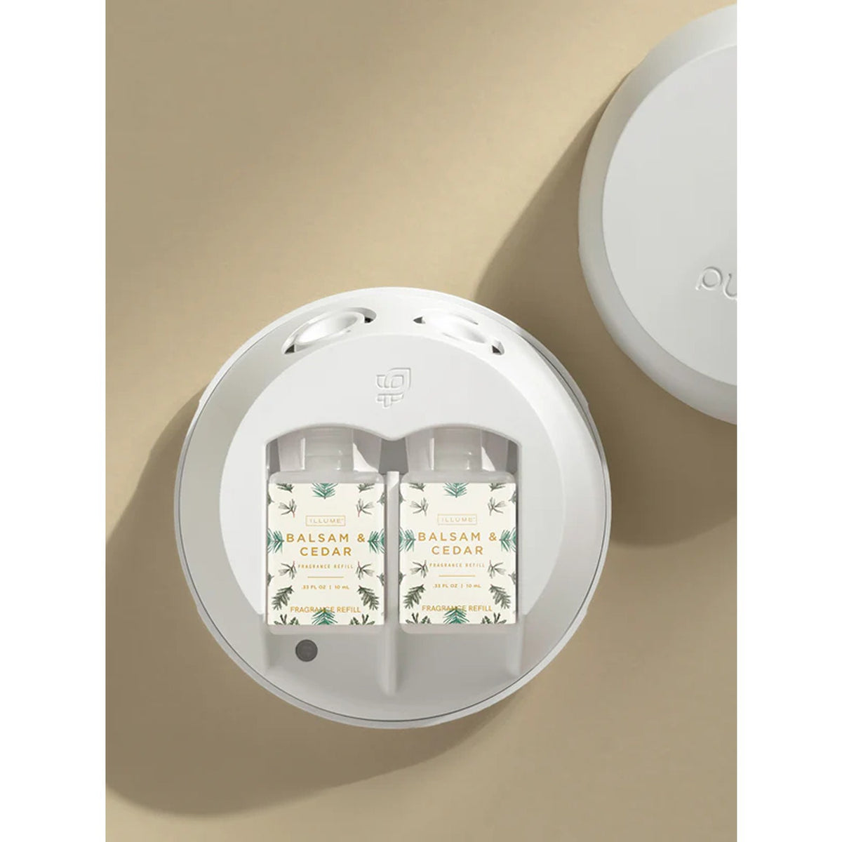 Two Illume Balsam & Cedar smart vials installed in a white Pura home diffuser